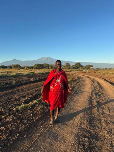 Maasai warrior walking along scenic road in Amboseli Np